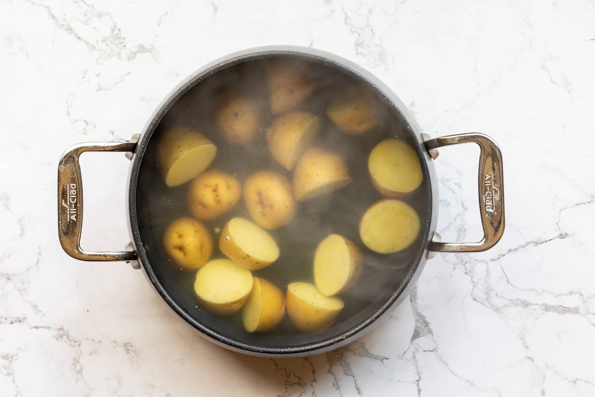 saucepan with potato halves boiling in water.