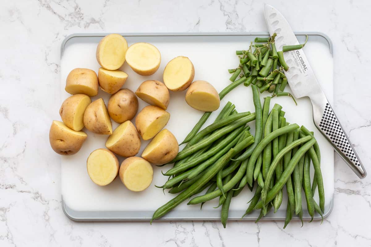 halved small potatoes and trimmed green beans on cutting board.