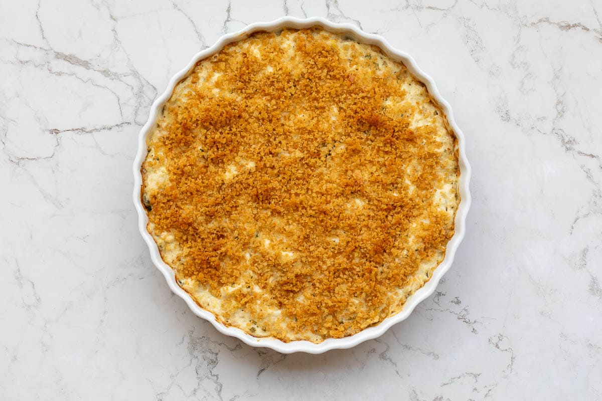 hot baked crab dip topped with breadcrumbs in baking dish.