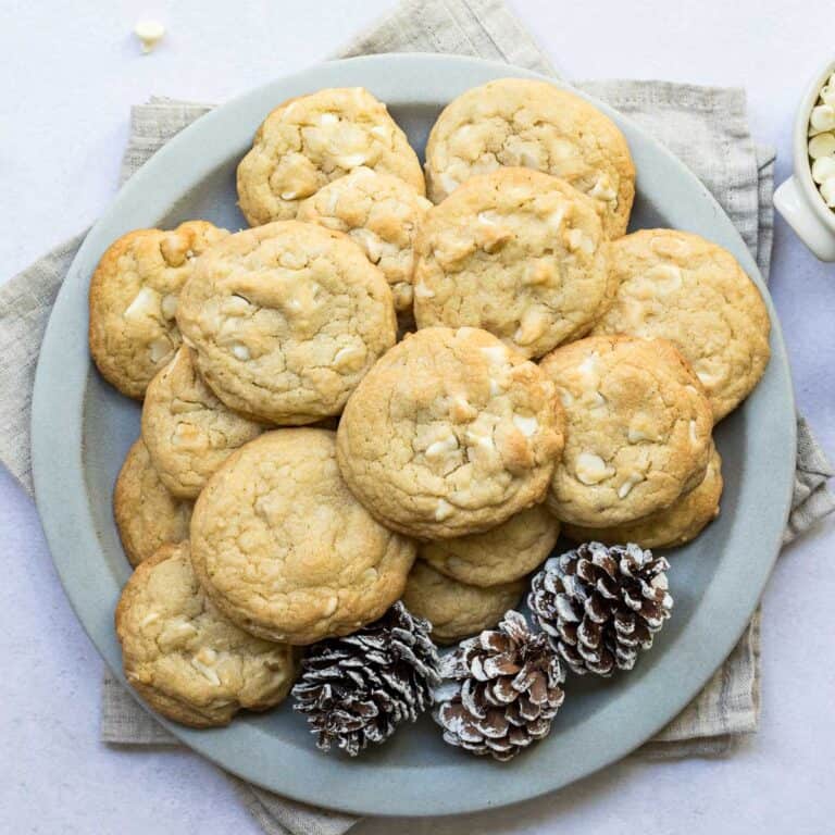 plate with pile of macadamia nut white chocolate cookies.