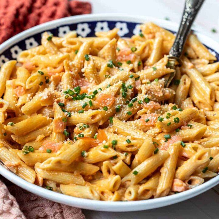 large pasta bowl filled with penne al salmon with serving spoon.