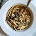 bowl of coq au vin blanc with spoon and thyme sprig.