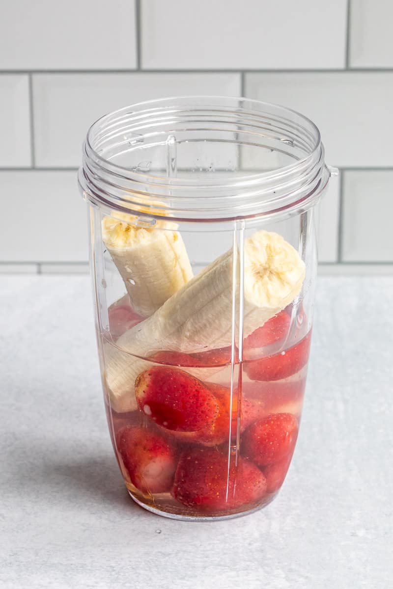 frozen strawberries, banana, and coconut water in a blender jar.