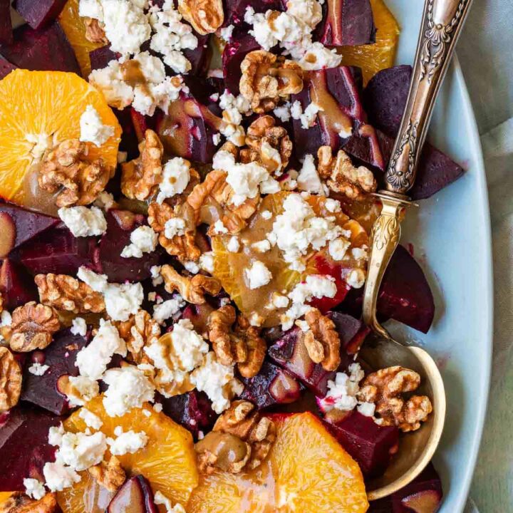 beet salad with feta cheese and walnuts in serving bowl with serving spoon.
