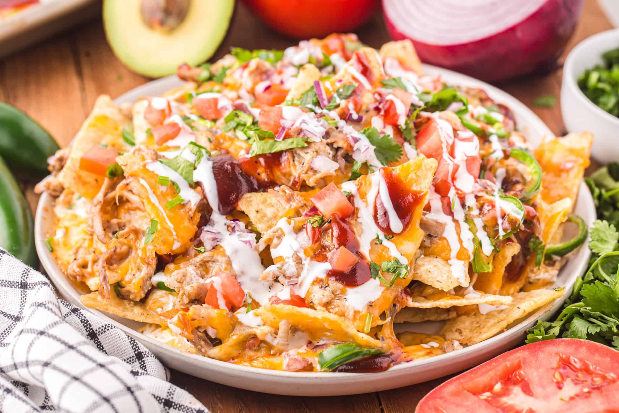platter of pulled pork nachos topped with sour cream and bbq sauce.