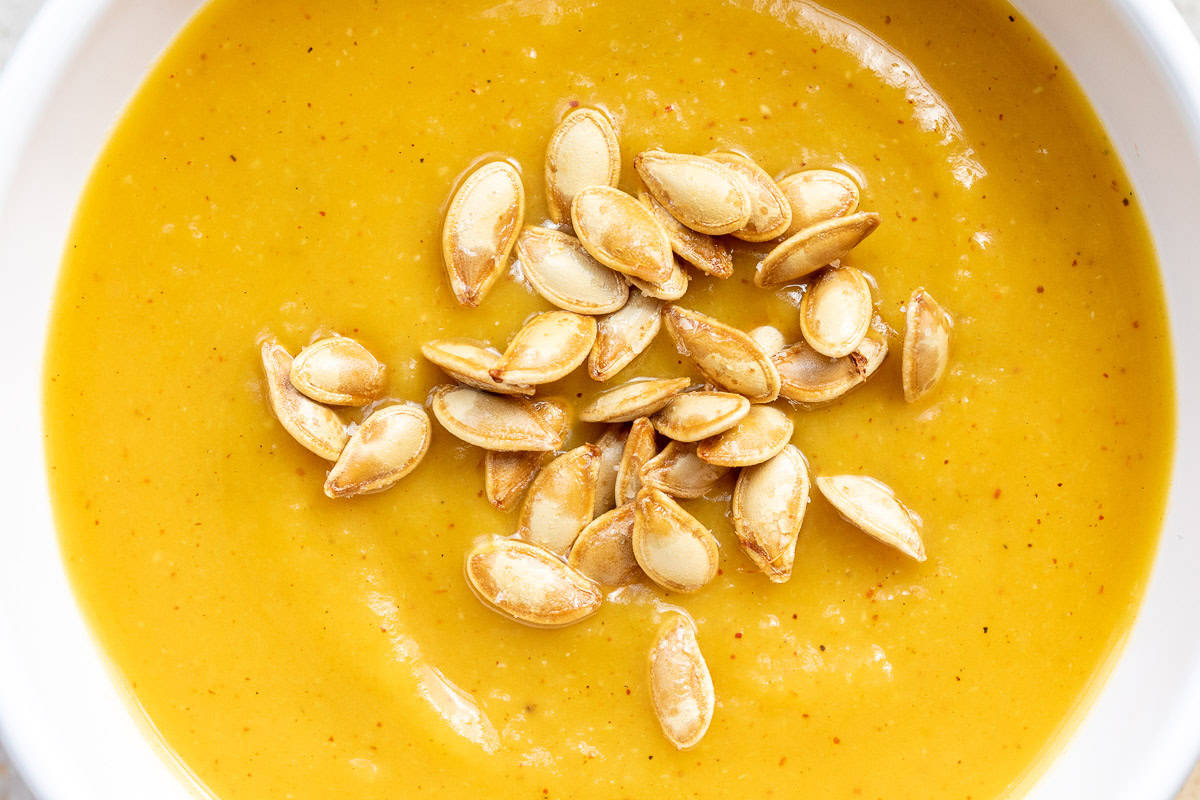 close up of overhead shot of bowl of pumpkin soup with toasted pumpkin seeds.