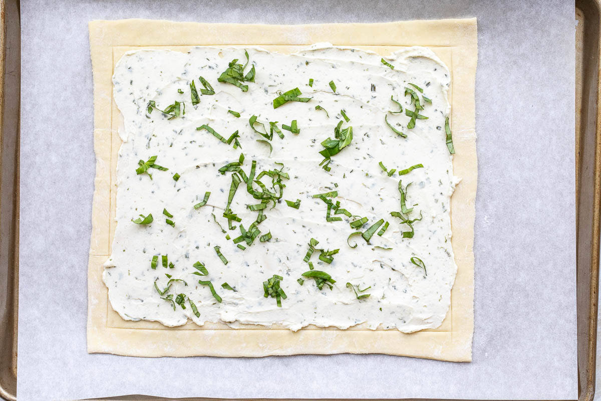 rolled out puff pastry dough topped with Boursin cheese and slivered basil.