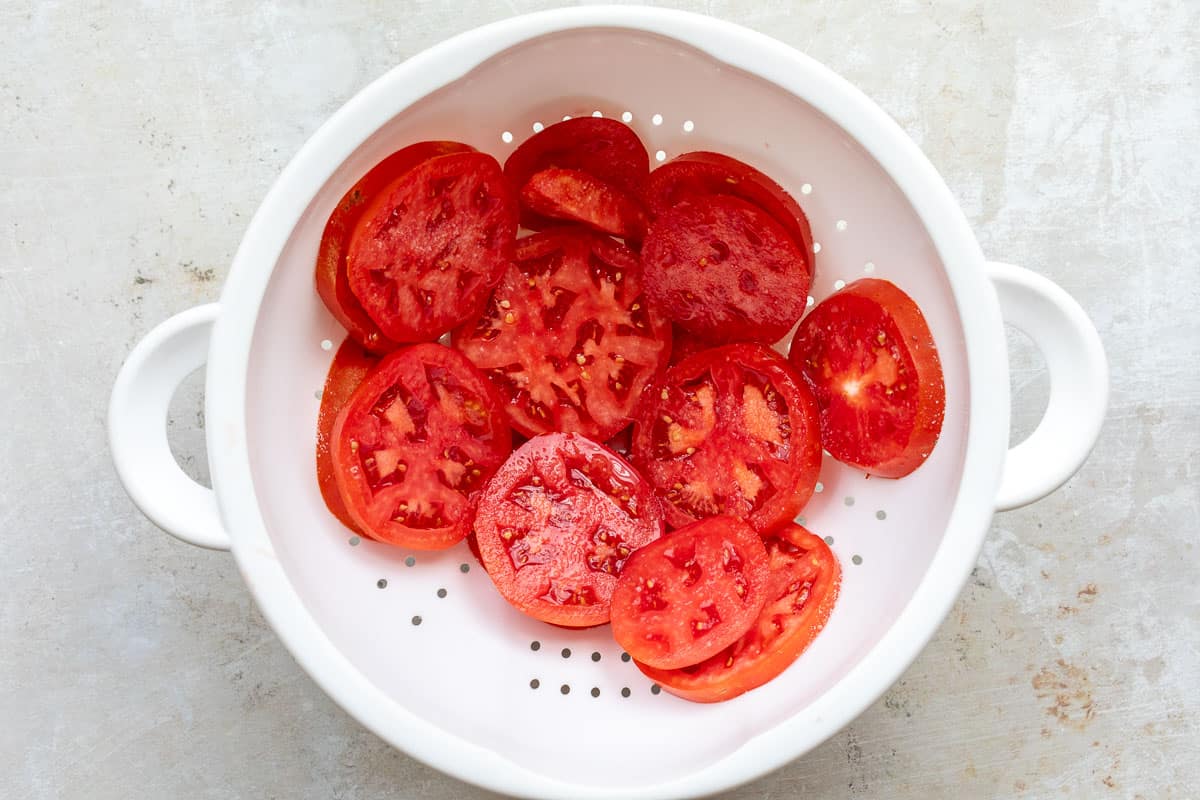 sliced tomatoes with salt in large strainer.