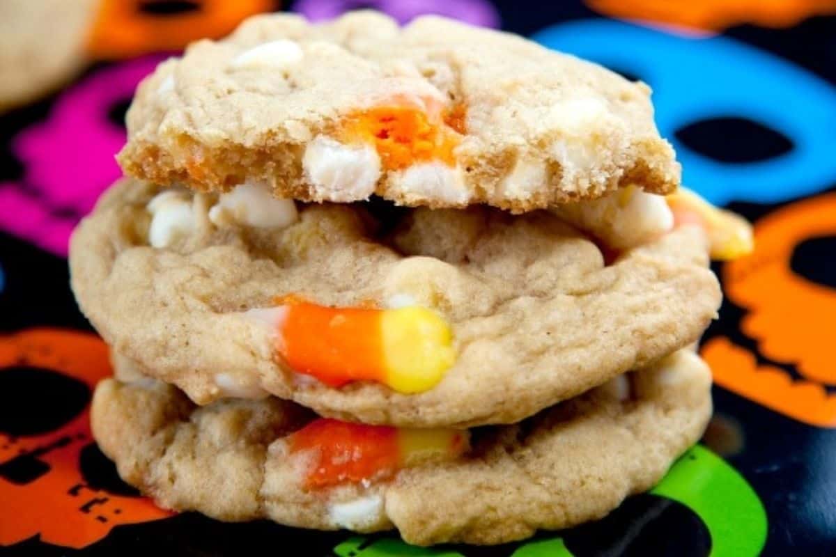 A stack of cookies with white chocolate chips and pieces of candy corn.