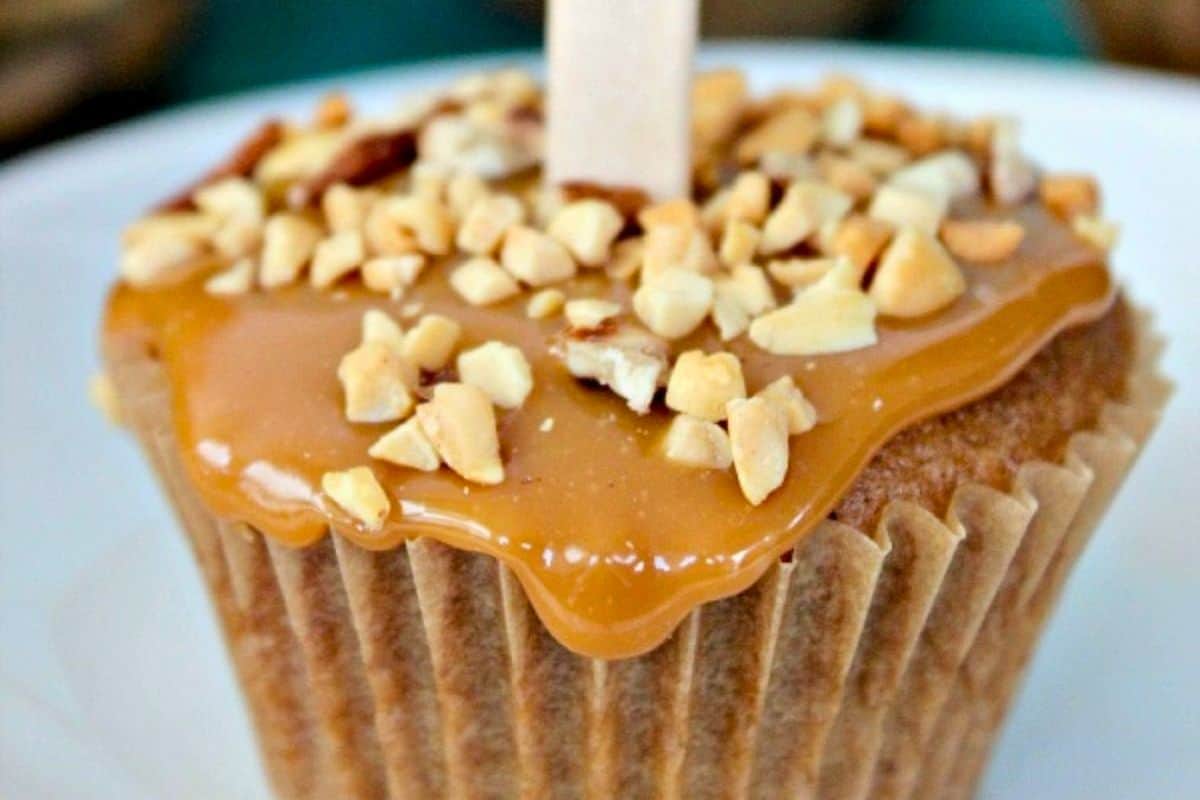 A cupcake topped with caramel frosting and chopped nuts.