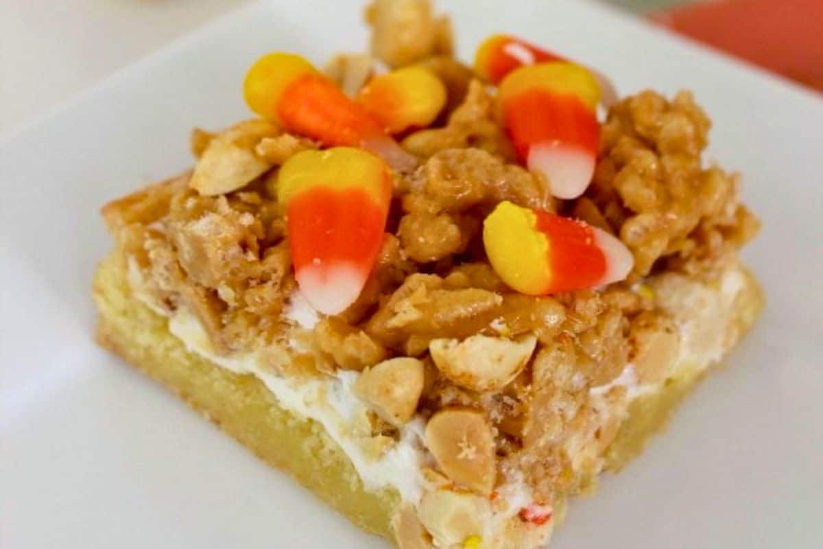 A dessert bar topped with peanuts, a crunchy caramel-like layer, and candy corn pieces.