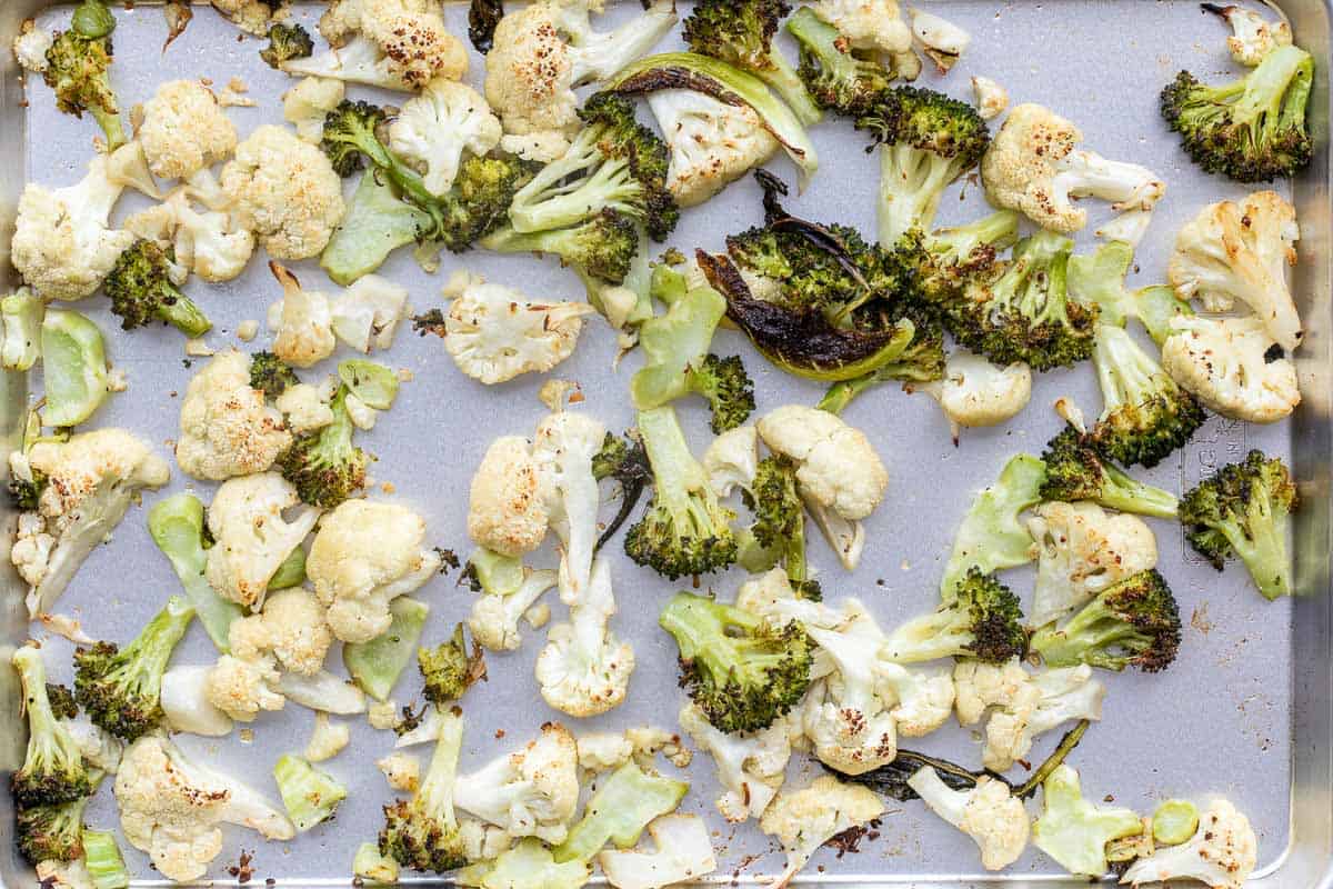 Roasted cauliflower and broccoli florets spread out on a baking sheet.