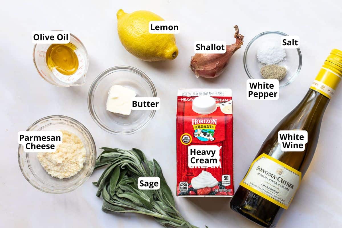 Ingredients for lobster ravioli sauce are arranged on a white surface, including olive oil, parmesan cheese, sage, butter, lemon, shallot, heavy cream, salt, white pepper, and white wine.