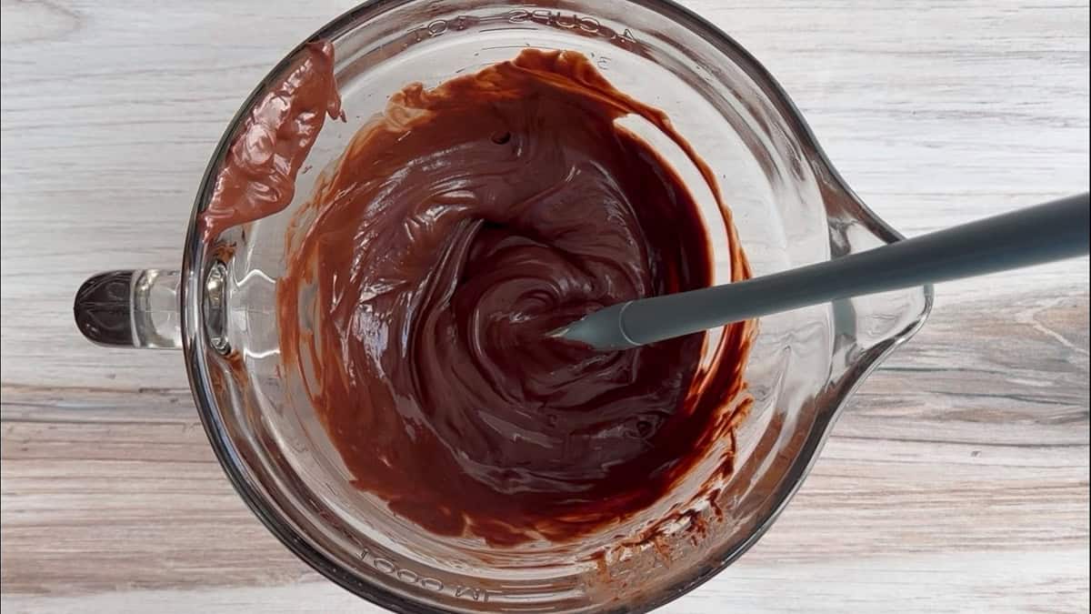 Melted chocolate and butter in glass bowl with spatula.