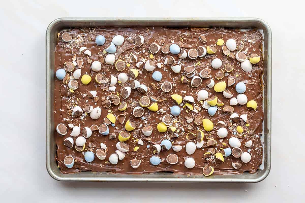 Saltine cracker toffee with Cadbury mini eggs on baking sheet.