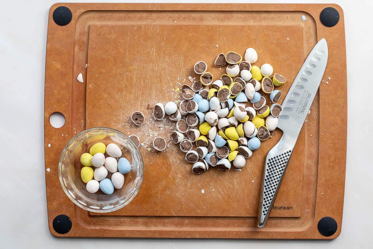 Chopped cadbury mini eggs on cutting board with knife.
