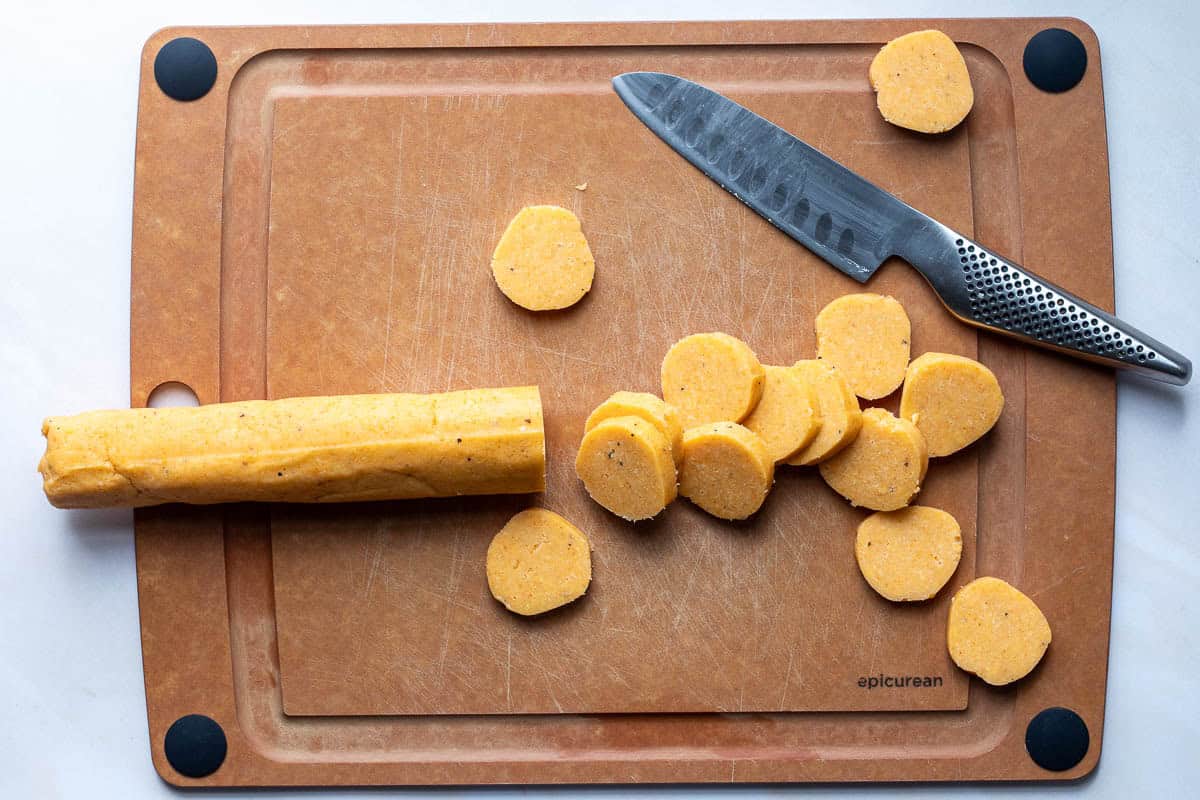 slicing cheese sables on cutting board with knife.