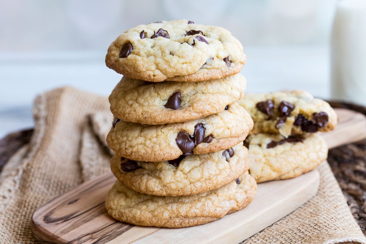 stack of brown butter chocolate chip cookies on cutting board sitting on burlap.