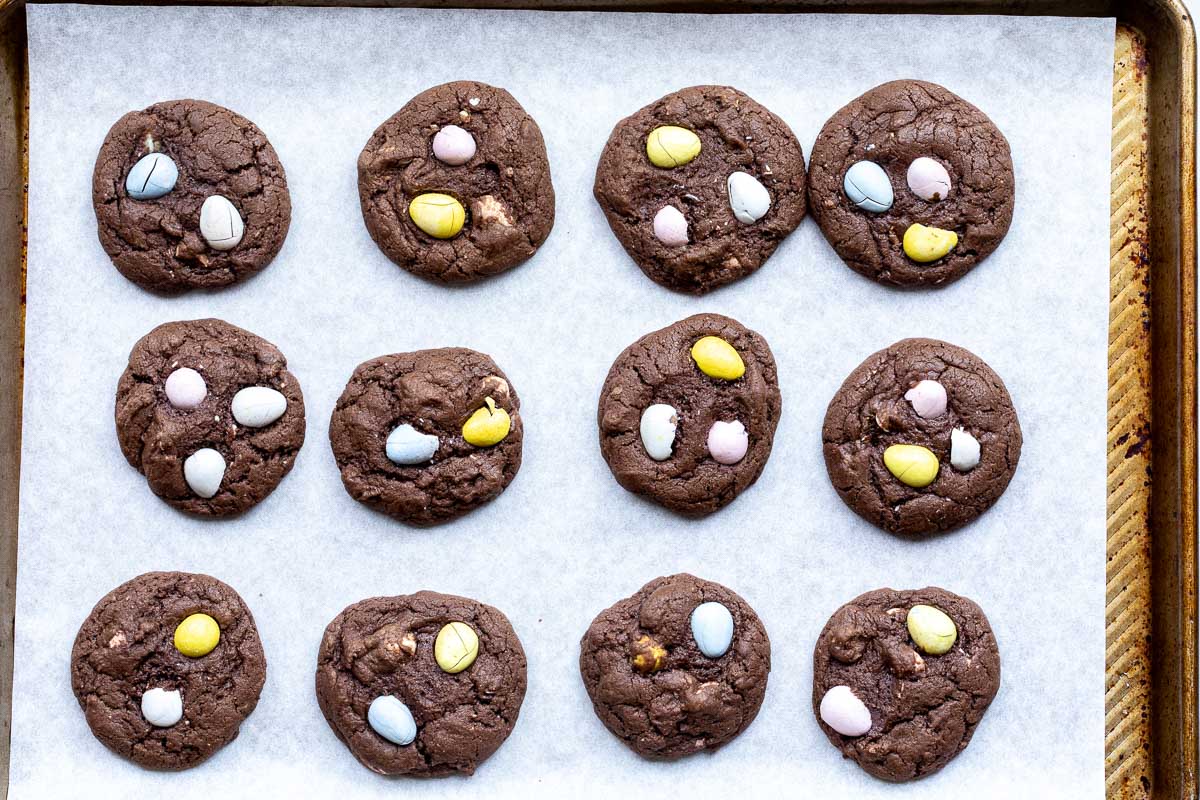 Baked chocolate mini Cadbury egg cookies on a parchment-lined sheet pan.