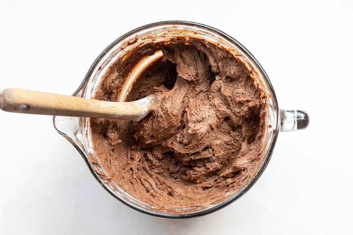 Batter for Cadbury mini egg cookies in mixing bowl with wooden spoon.
