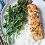 Delicious grilled salmon served with fresh kale and white rice on a ceramic plate, highlighting healthy and flavorful meal options.