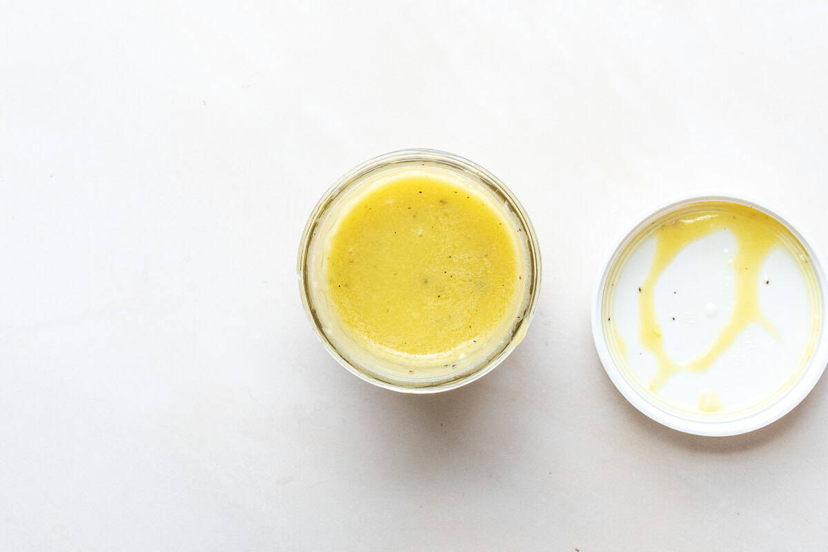 Overhead view of jar of citrus vinaigrette with lid next to it.