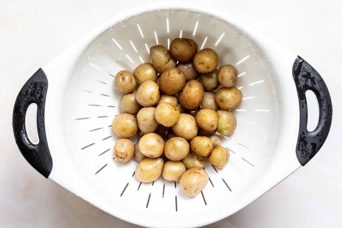 Small, unpeeled potatoes in a white colander.